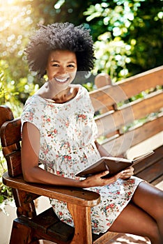 African woman, smile and book on park bench in portrait to relax on vacation with story, language and learning. Girl