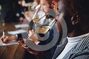 African woman sommelier bartender smelling white wine and making degustation card