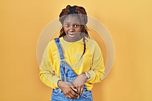 African woman standing over yellow background afraid and shocked with surprise and amazed expression, fear and excited face