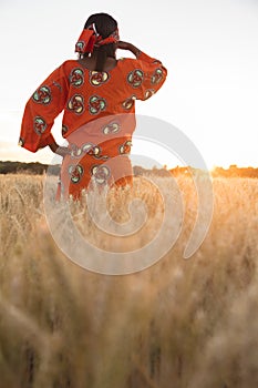 African woman in traditional clothes looking in a field of crops