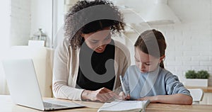 African woman tutor helping caucasian child with homework at home