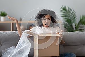 African woman unpack parcel feels angry see broken ordered goods