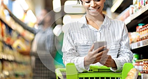 African Woman Using Grocery Shopping App On Smartphone In Supermarket