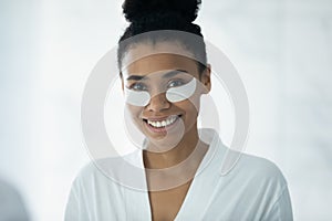 African woman using hydrogel recovery patches for perfect undereye skin photo
