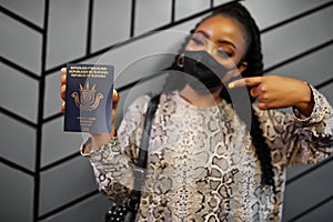 African woman wearing black face mask show Burundi passport in hand. Coronavirus in Africa country, border closure and quarantine