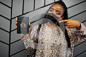 African woman wearing black face mask show Republic of the Congo passport in hand. Coronavirus in Africa country, border closure