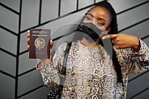 African woman wearing black face mask show Senegal passport in hand. Coronavirus in Africa country, border closure and quarantine photo
