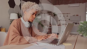 African woman wearing wireless headphones watching webinar with online teacher