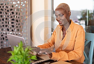 African woman working on laptop in bar restaurant - Afro female typing on computer