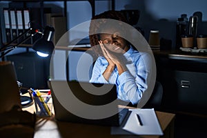 African woman working at the office at night sleeping tired dreaming and posing with hands together while smiling with closed eyes