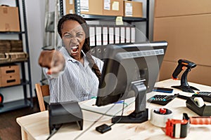 African woman working at small business ecommerce pointing displeased and frustrated to the camera, angry and furious with you