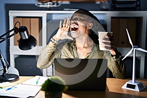 African woman working using computer laptop at night shouting and screaming loud to side with hand on mouth