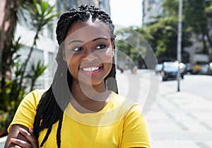 African woman in a yellow shirt in city looking sideways