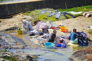 African women washing clothes on a river. Washed clothes are lie