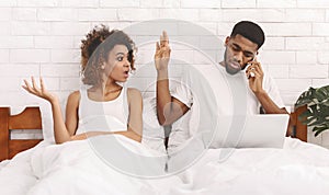 African workaholic husband ingnoring his iiritated wife in bed