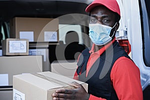 African worker delivering boxes while wearing safety mask during coronavirus outbreak - Focus on face