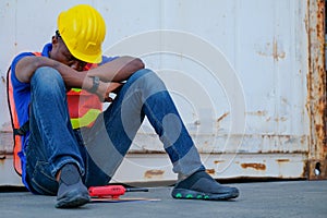 African worker man sit close to cargo container and he look tire and also sleepy