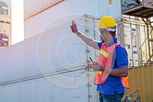 African worker man stand and lift hand and show hand symbol of stop for truck in cargo container shipping area
