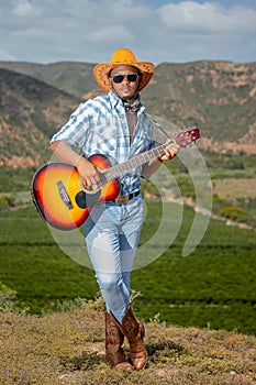 An African Xhosa cowboy in the countryside of South Africa playing his guitar.