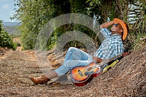 An African Xhosa Cowboy relaxing on a country road in South Africa with his guitar.