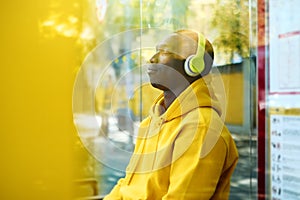 African Young Man Listening To Music At Bus Stop