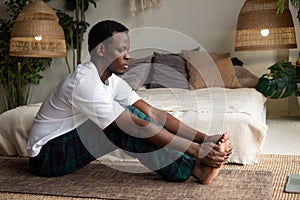 African young man sitting in paschimottanasana or Intense Dorsal Stretch pose, seated forward bend posture
