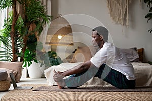 African young man sitting in paschimottanasana or Intense Dorsal Stretch pose, seated forward bend posture