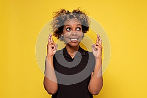 African young woman with fingers crossed, wishing or praying about something