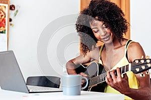 african young woman learning to play guitar with online lessons
