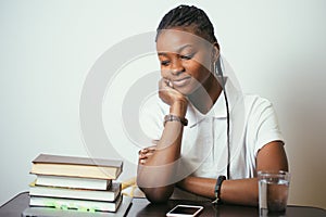 African young woman sitting at table with books at home