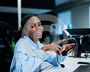 African young woman smiling and holding a headset in her hands. Call center employee.