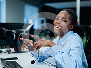 African young woman smiling and holding a headset in her hands. Call center employee.