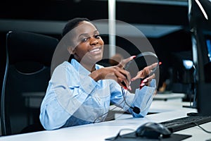 African young woman smiling and holding a headset in her hands. Call center employee.