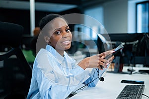 African young woman smiling and holding a headset in her hands. Call center employee.