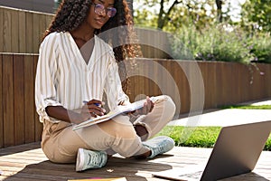 African young woman student learning using laptop studying outside campus.