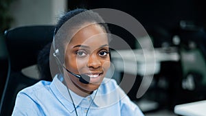 African young woman talking to a client on a headset. Female employee of the call center.