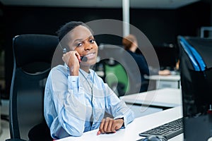 African young woman talking to a client on a headset. Female employee of the call center.