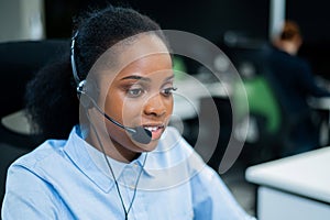 African young woman talking to a client on a headset. Female employee of the call center.