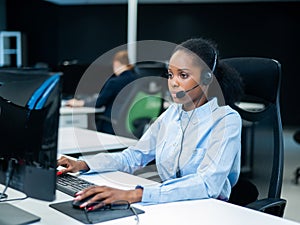 African young woman talking to a client on a headset. Female employee of the call center.