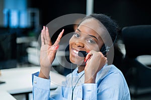 African young woman talking to a client on a headset. Female employee of the call center.