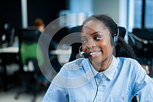 African young woman talking to a client on a headset. Female employee of the call center.