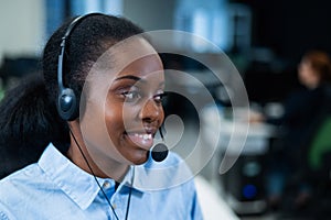 African young woman talking to a client on a headset. Female employee of the call center.