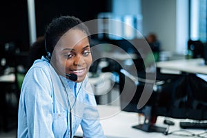 African young woman talking to a client on a headset. Female employee of the call center.