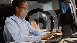 African young woman typing on a computer at her desk in the office.