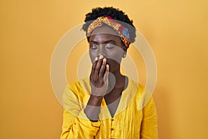 African young woman wearing african turban bored yawning tired covering mouth with hand