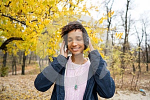 Africanamerican girl listening to music in the autumn park