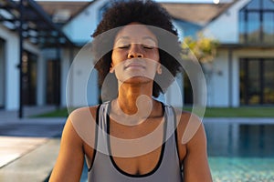 Afro african american young woman with eyes closed practicing yoga in backyard