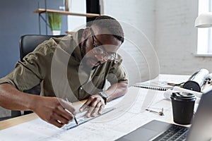 Afro-American architect working in office with blueprints.Engineer inspect architectural plan, sketching a construction