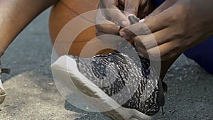 Afro-american basketball player tying his shoelaces before the game, close up