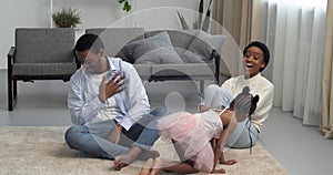 Afro American black ethnic family sitting at home on living room floor young parents mom and dad with daughter at home